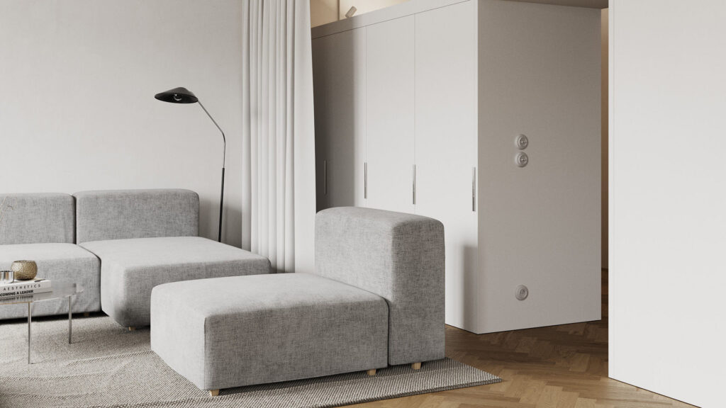 Szara sofa modułowa i biała zabudowa w jasnym salonie